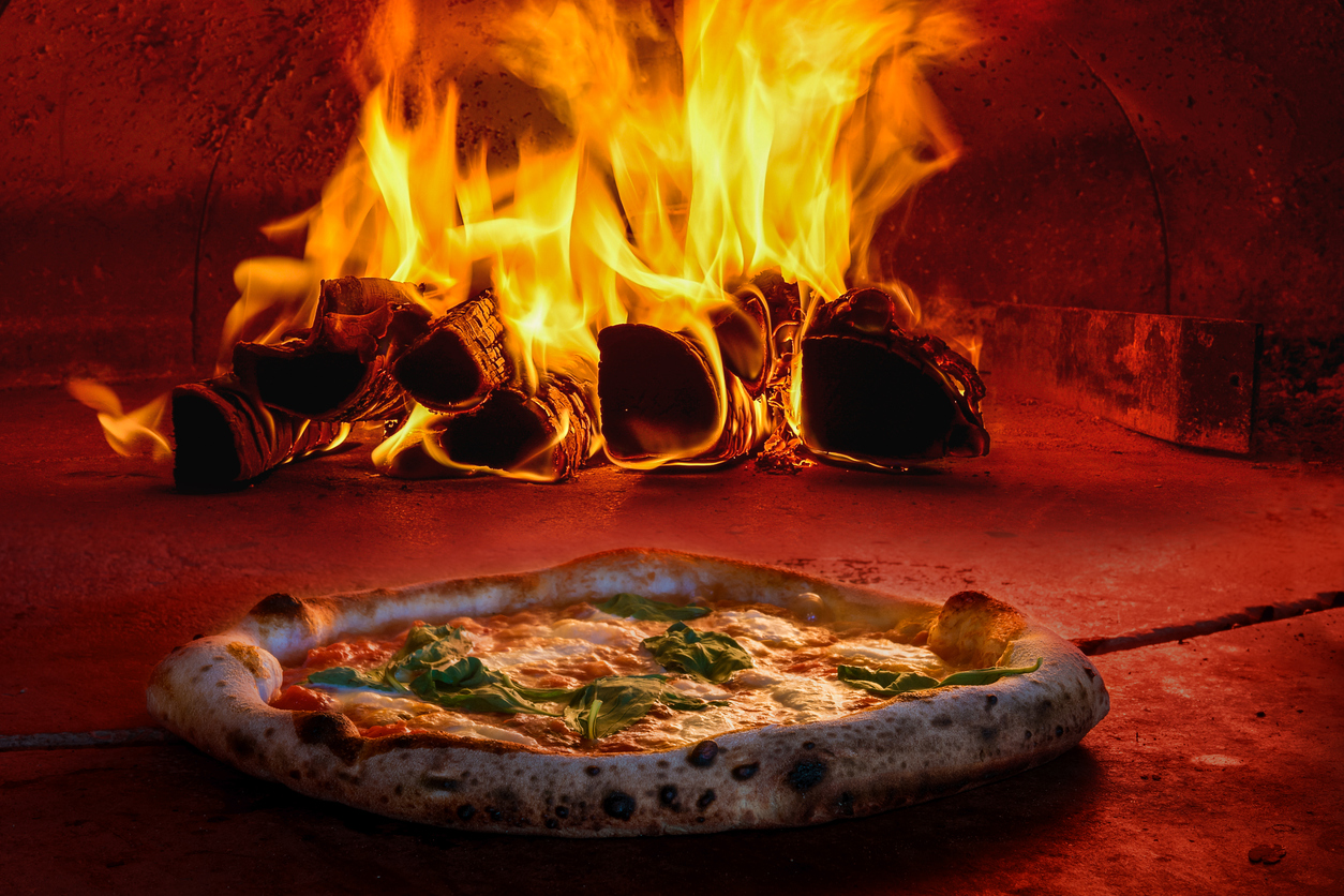 pizza being placed in a wood fired oven