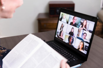 A woman uses her laptop at home to video conference with her friends for their monthly book club: apartments in Lone Tree