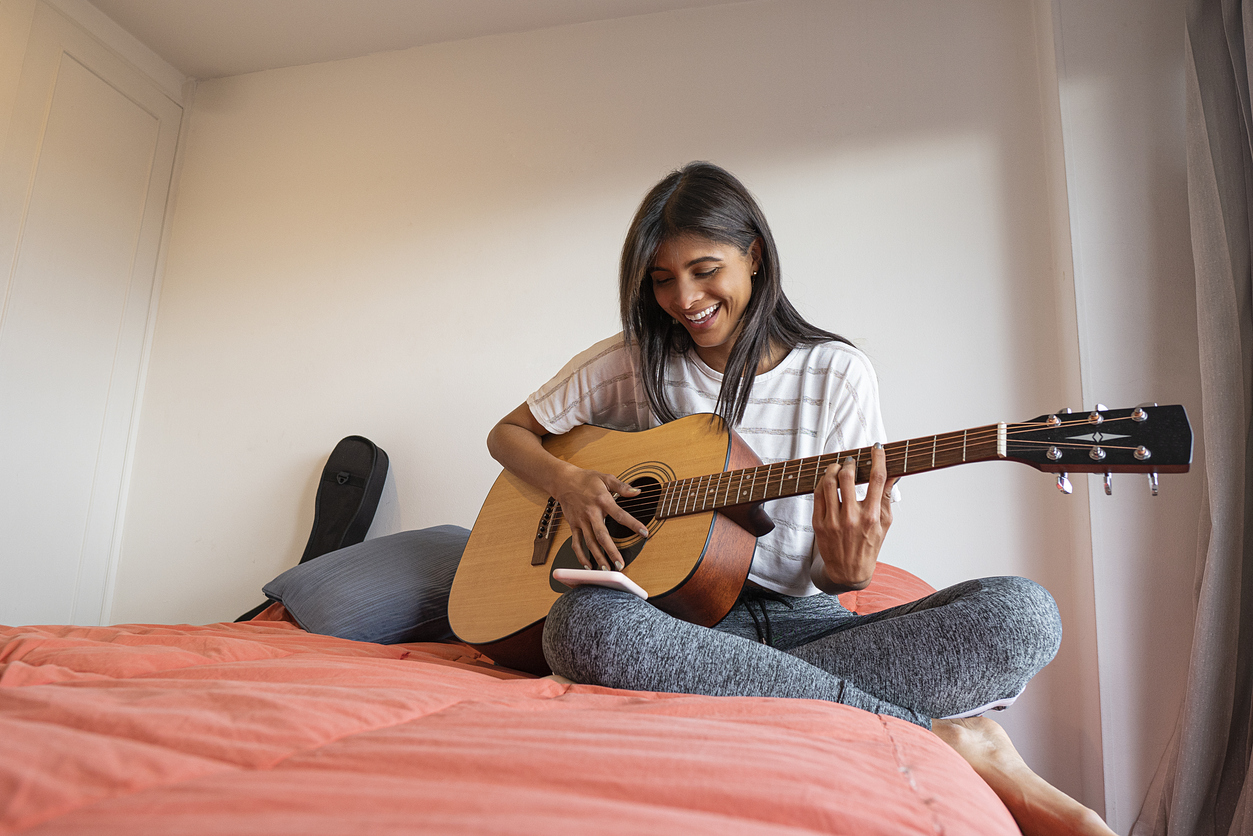 woman playing a guitar in her room | virtual music classes around Lone Tree