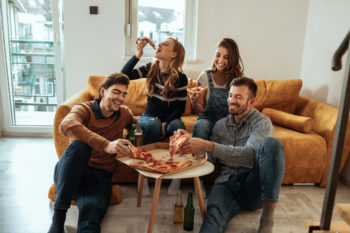 friends enjoying delivered pizza in a living room | pizza delivery in Lone Tree
