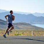 man running on pavement with hills and water in the background | running clubs Lone Tree