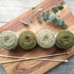 four balls of yarn and hooks on a wooden table | knitting Lone Tree